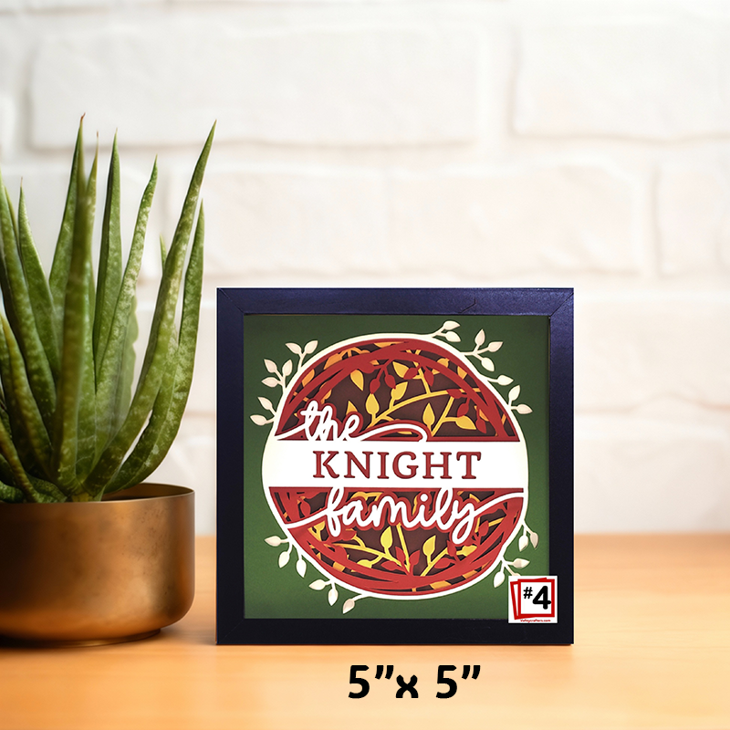 Framed decorative sign with 'the KNIGHT family' text on a wooden surface with a plant.