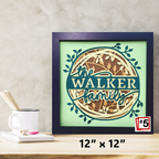 Framed artwork with 'the WALKER family' text on a light green background, displayed on a wooden surface.