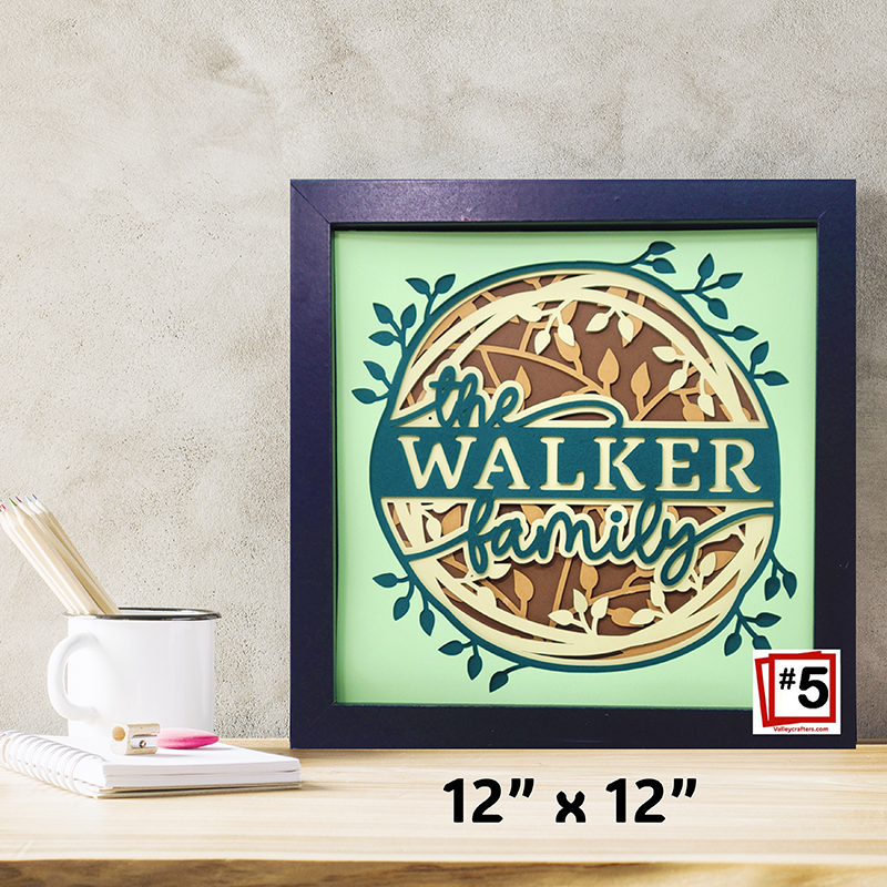 Framed artwork with 'the WALKER family' text on a light green background, displayed on a wooden surface.