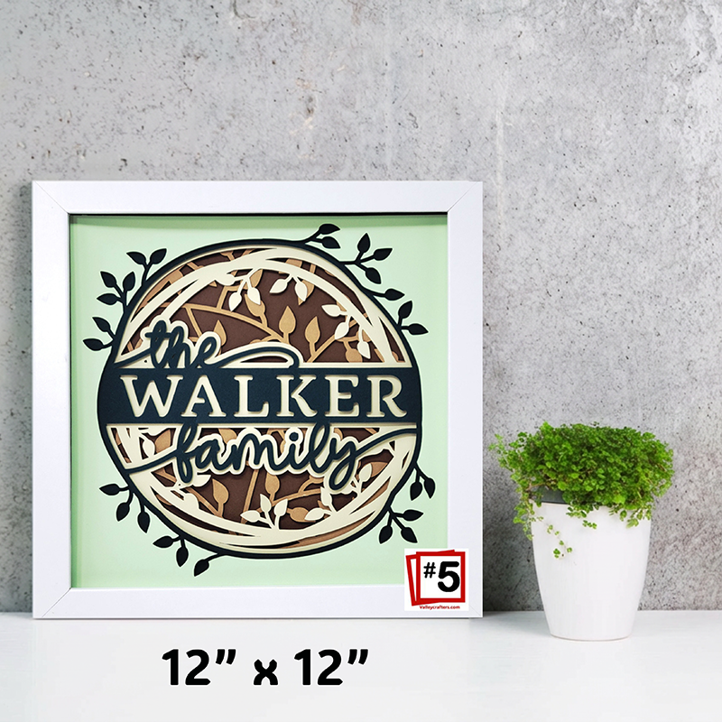 Framed artwork with 'The Walker Family' design on a light green background, next to a potted plant.