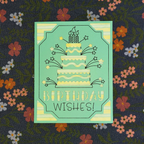 Greeting card with birthday cake illustration and 'Birthday Wishes!' text on a floral fabric background.