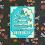 Greeting card with birthday cake illustration and 'Have a lovely birthday' text on a floral background.