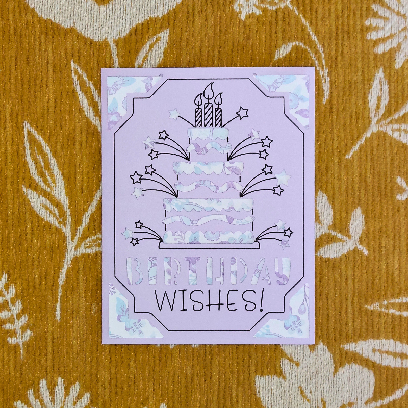 Purple birthday card with cake and candles design on a patterned orange background