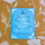 Blue birthday card with cake and candles design on a textured yellow background