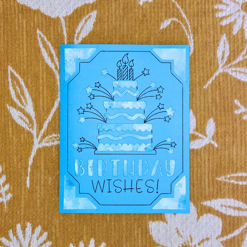 Blue birthday card with cake and candles design on a textured yellow background