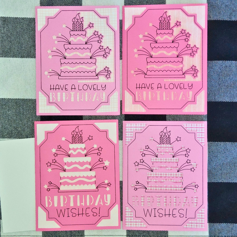 Four pink birthday cards with cake illustrations on a checkered fabric background.