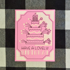 Pink birthday card with cake illustration and 'Have a Lovely Birthday' text on a checkered background.