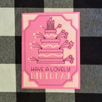 Pink birthday card with cake illustration and text on a checkered fabric background