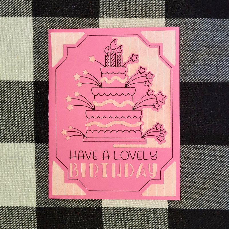 Pink birthday card with cake illustration and text on a checkered fabric background