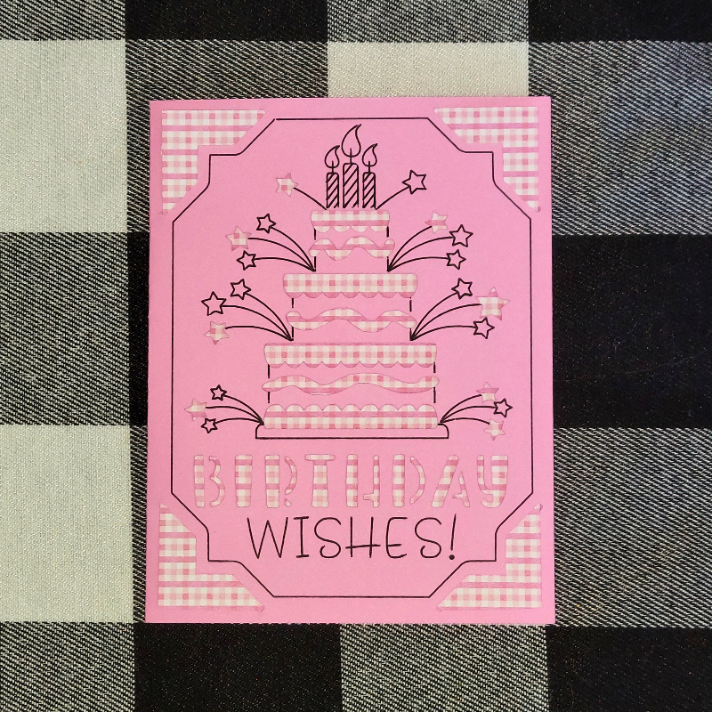 Pink birthday card with cake and candles design on a checkered background