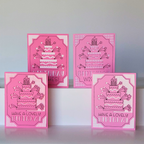 Four pink birthday cards with cake illustrations on a white surface.