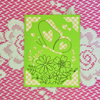 Green card with floral and heart designs on a pink and white patterned background