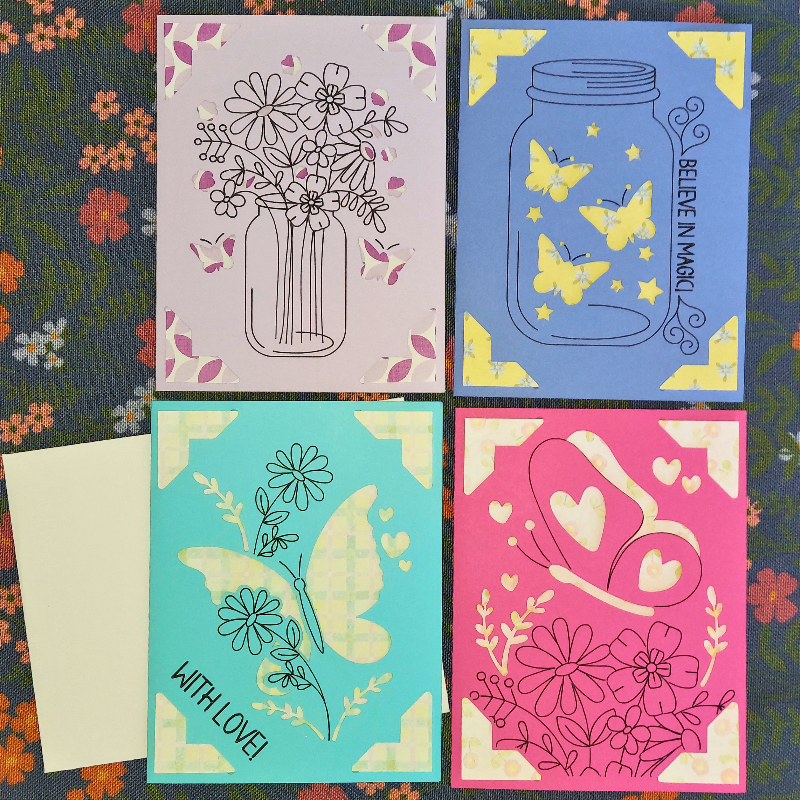 Four colorful greeting cards with floral, butterfly, and heart designs on a patterned background.