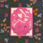 Decorative card with floral and heart designs on a pink background, placed on a fabric with floral patterns.