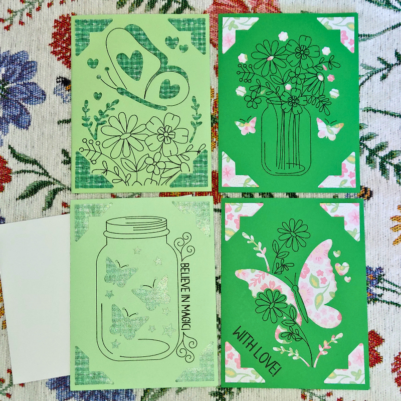 Four green cards with floral and butterfly designs on a floral background