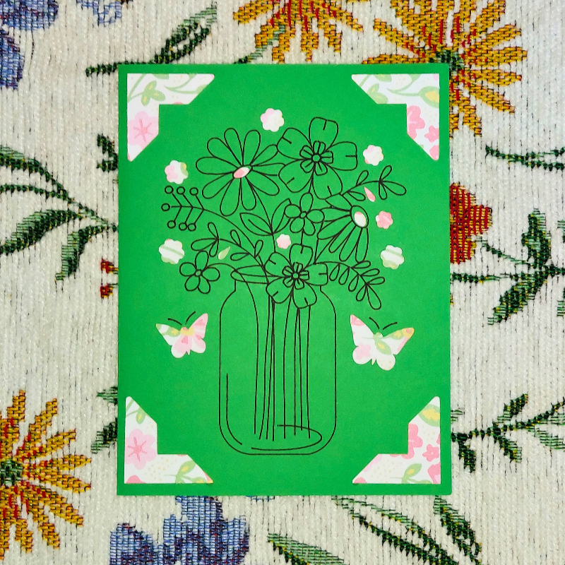 Green card with black line drawing of a vase of flowers and butterflies on a floral-patterned background.