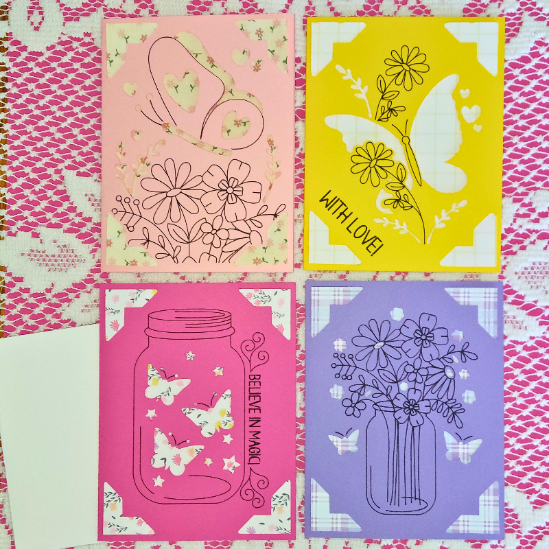 Four decorative greeting cards with floral and butterfly designs on a pink and white patterned background.