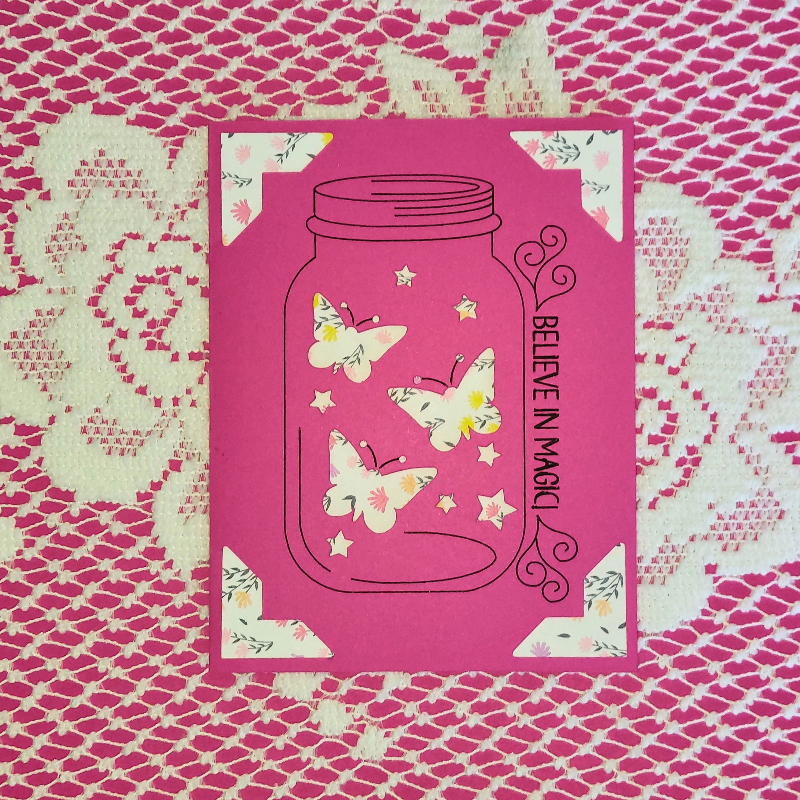 Pink card with butterfly design and 'Believe in Magic' text on a pink and white patterned background