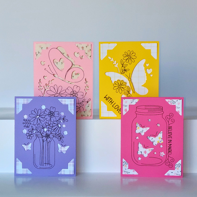 Four colorful greeting cards with floral and butterfly designs on a light gray background.