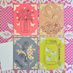 Four decorative cards with floral and butterfly designs on a lace background.