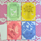 Four colorful cards with illustrations on a patterned background