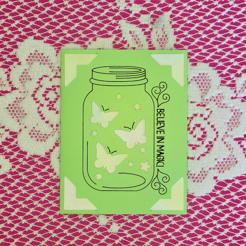 Green card with butterfly design and 'Believe in Magic' text on a pink and white patterned background