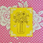 Yellow card with black floral design on a pink lace background
