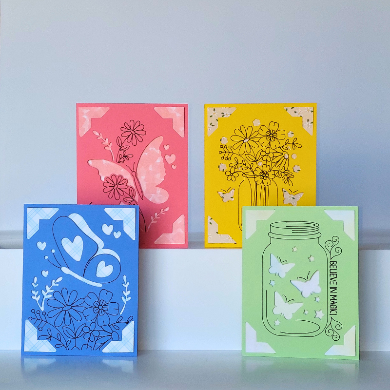 Four colorful greeting cards with floral and butterfly designs on a light blue background.