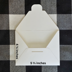 White envelope with dimensions labeled on a black and white checkered background
