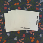 White cards with measurements on a floral-patterned fabric background