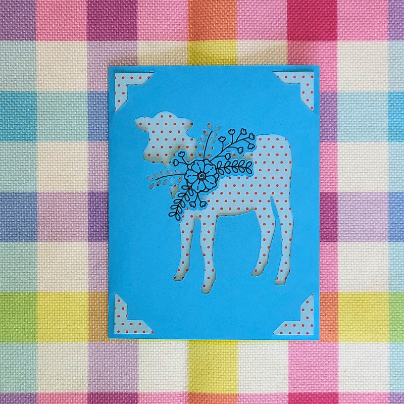 Card with a polka dot cow design on a colorful checkered background