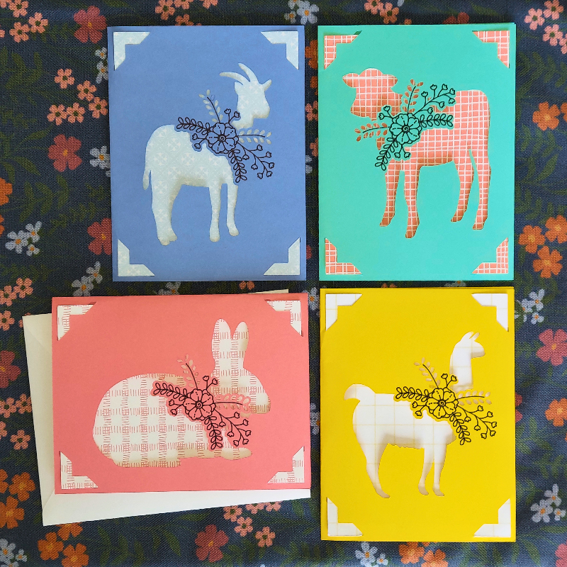 Four colorful greeting cards with animal illustrations on a floral background