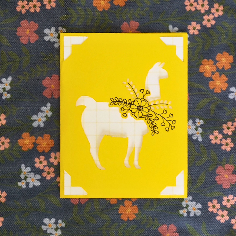 Yellow card with a white llama design on a floral background