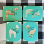 Four greeting cards with animal illustrations on a checkered fabric background