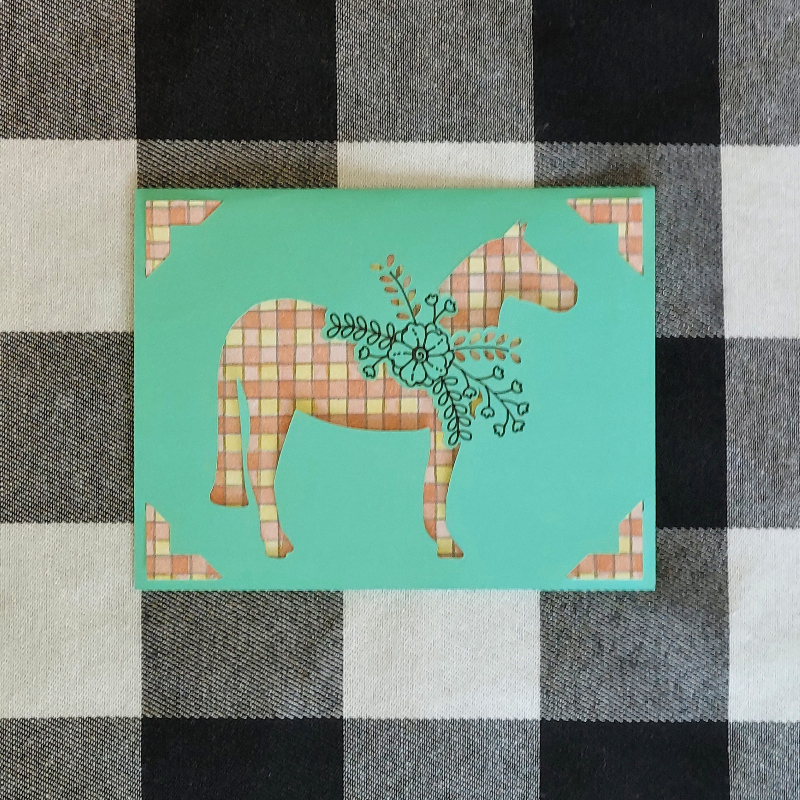 Card with a stylized horse design on a checkered fabric background