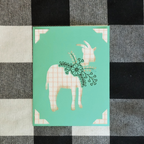 Card with a patterned goat design on a checkered fabric background