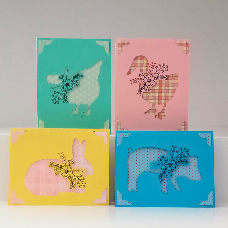 Four colorful greeting cards with animal illustrations on a white surface.