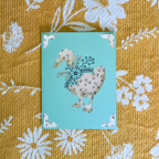 Card with a floral design on a duck on a textured yellow fabric background