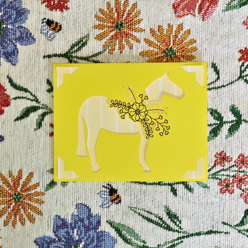 Yellow card with a horse illustration on a floral patterned background