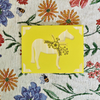 Yellow card with a horse illustration on a floral patterned background