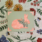 Card with a pink rabbit design on a floral patterned background