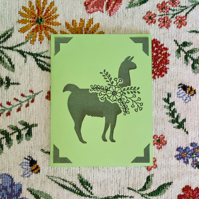 Green card with llama design on a floral background
