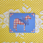 Card with red and white patterned horse design on a blue background, placed on a yellow and white textured fabric.