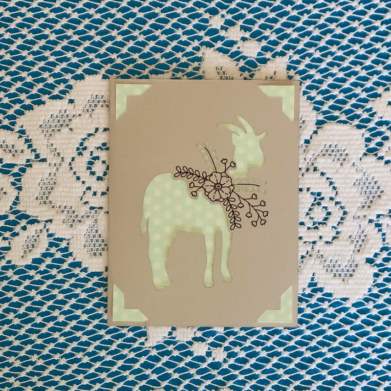 Decorative card with a goat illustration on a textured fabric background