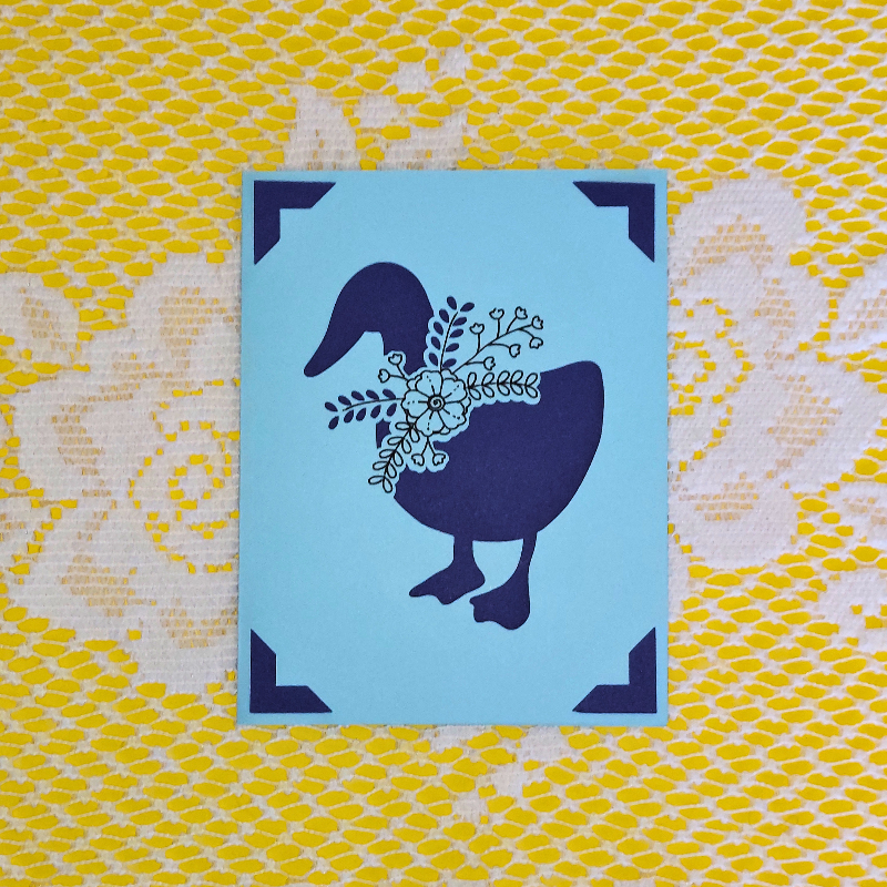 Blue card with a goose design on a yellow and white patterned background