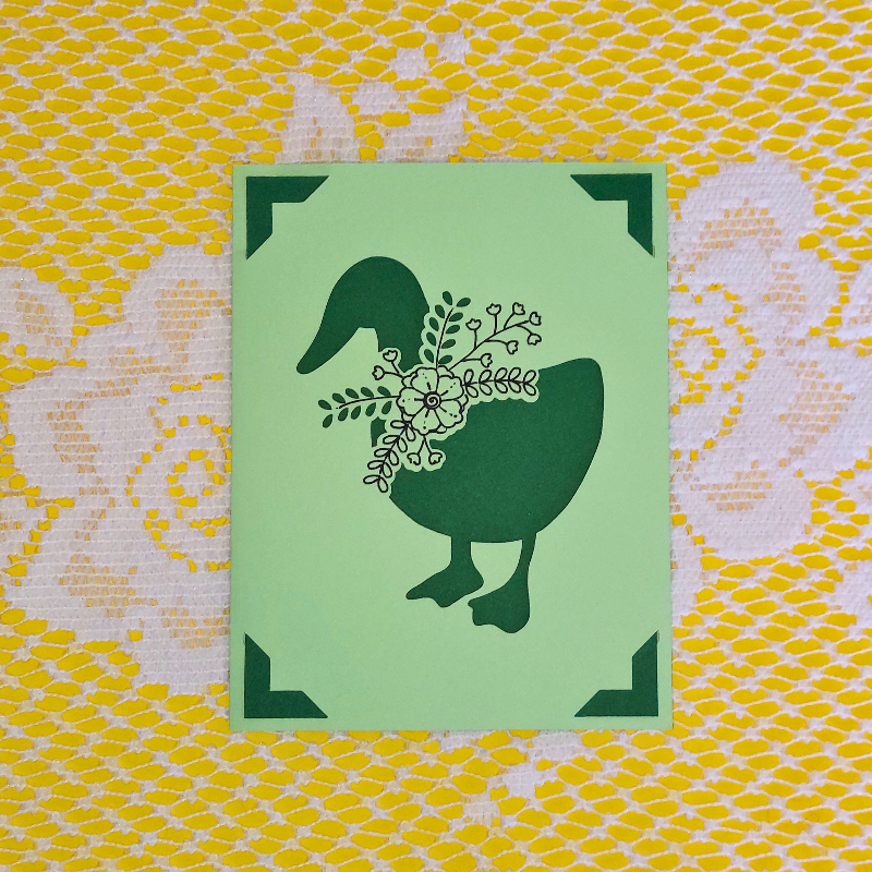 Green card with a greem goose design on a yellow and white patterned background