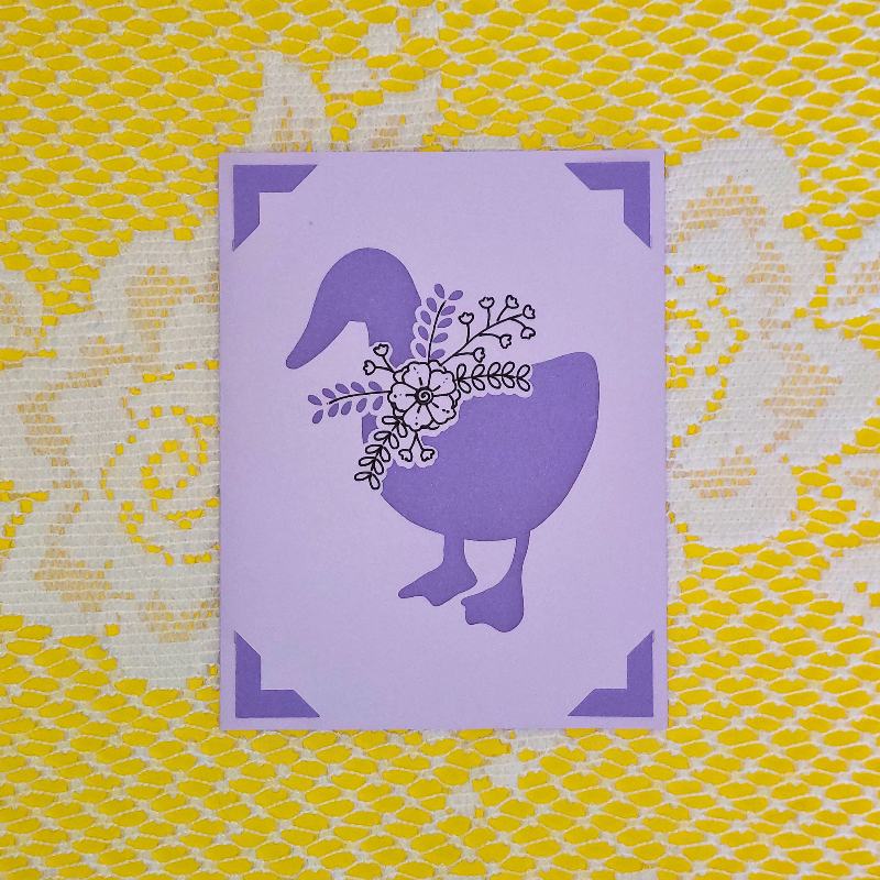 Purple card with a goose design on a yellow and white patterned background