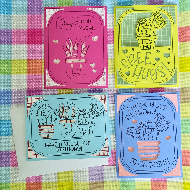 Four colorful greeting cards with cactus designs on a checkered fabric background.