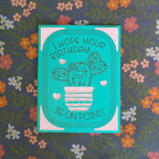 Teal birthday card with cactus illustration on a floral background